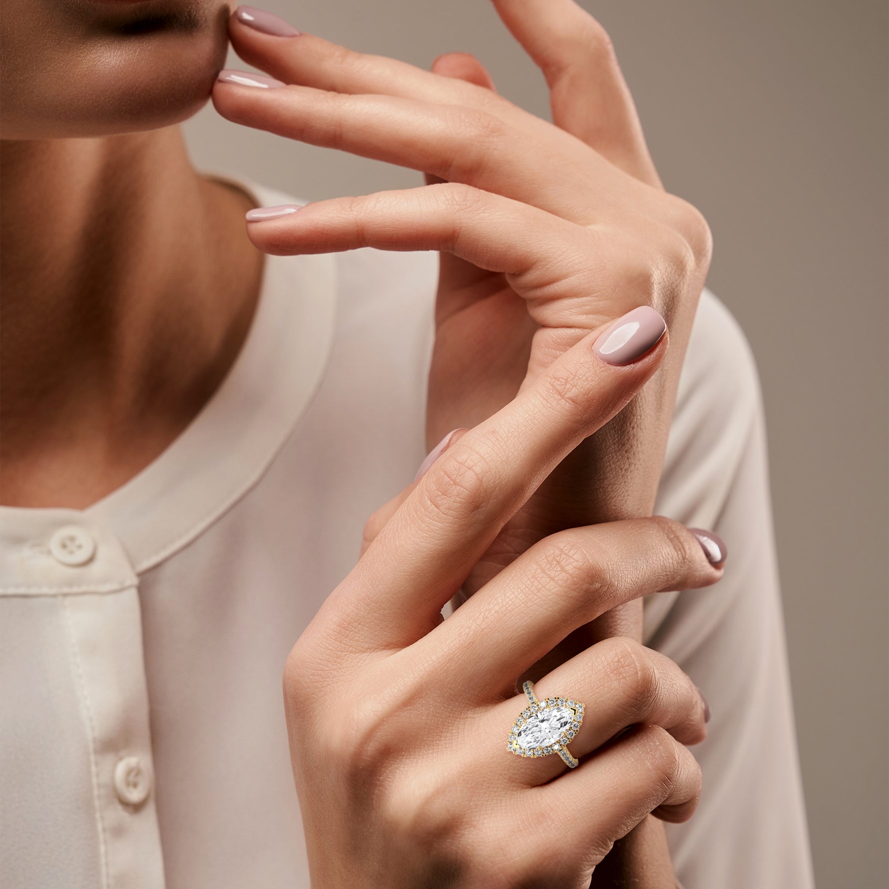 Close-up of a woman's hand wearing a diamond ring on a neutral background 