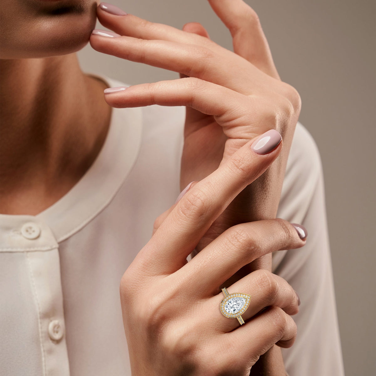 Close-up of a woman's hand wearing a gold ring with a diamond on a neutral background 