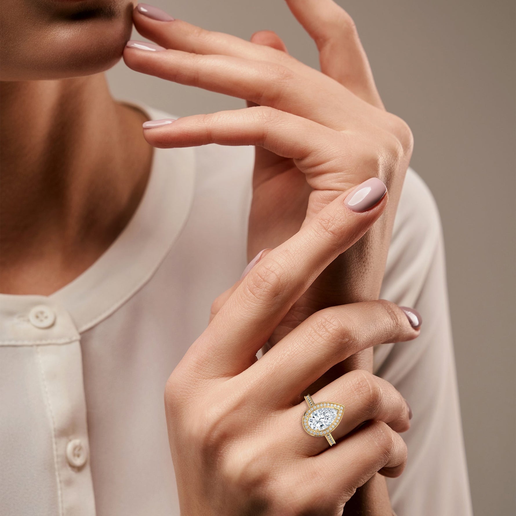 Close-up of a woman's hand wearing a gold ring with a diamond on a neutral background 