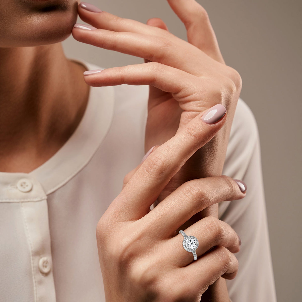 Close-up of a woman's hand wearing a diamond ring on a neutral background 